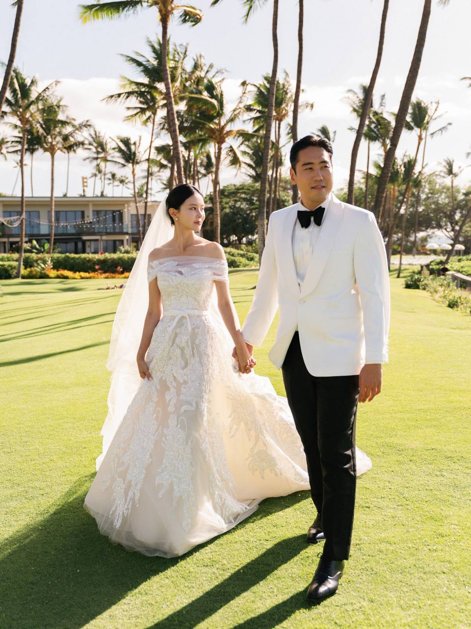 Bride and groom walking together on a palm-lined lawn