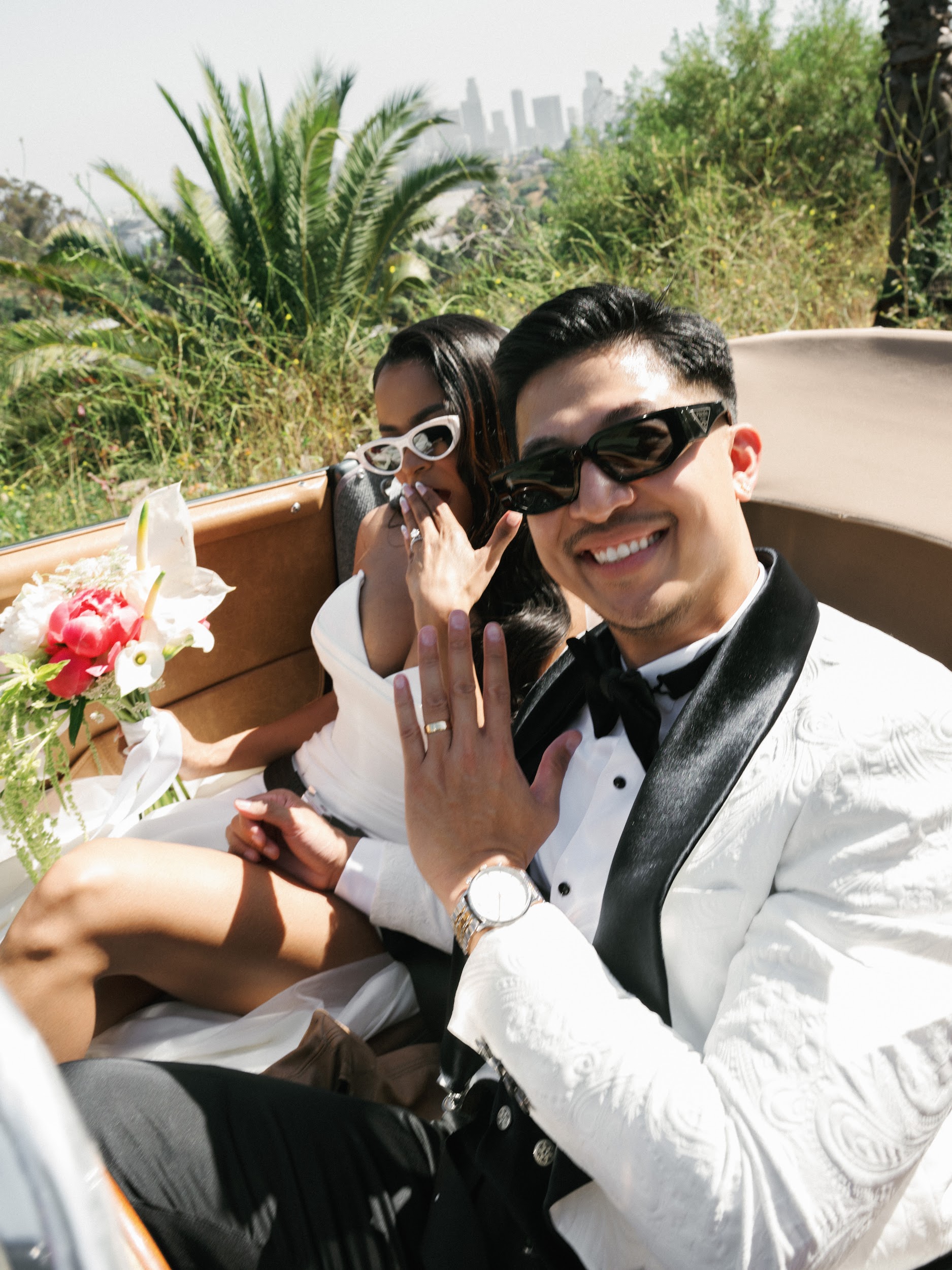 Newlyweds taking a joyful car selfie after their wedding