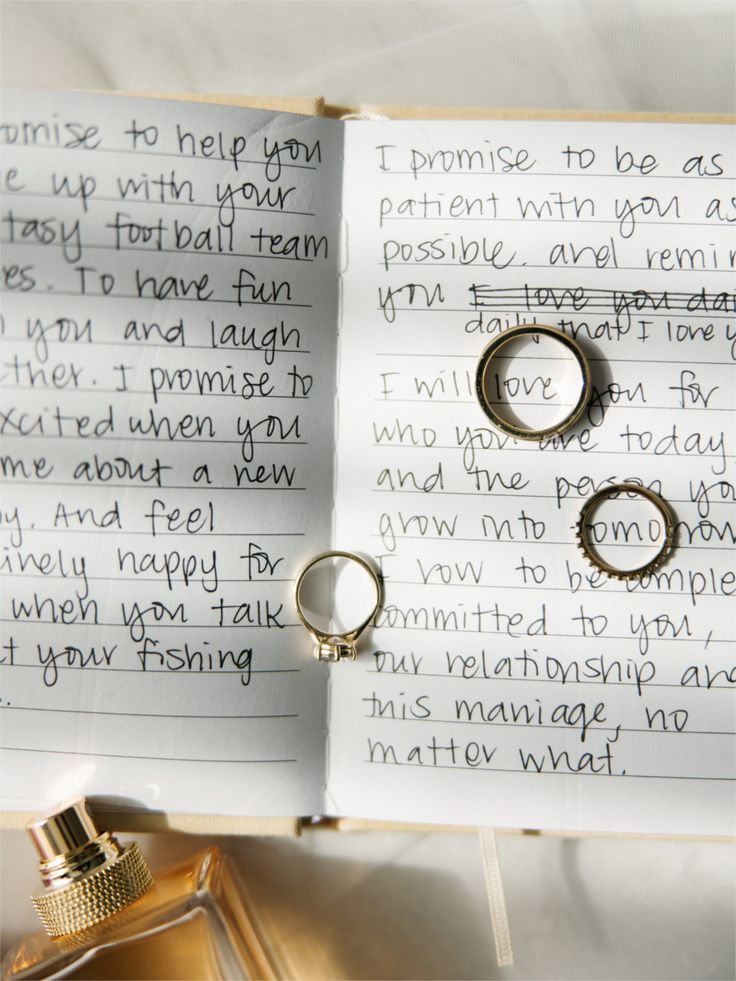 Close-up of handwritten wedding vows in a notebook with gold and silver wedding rings on the pages.
