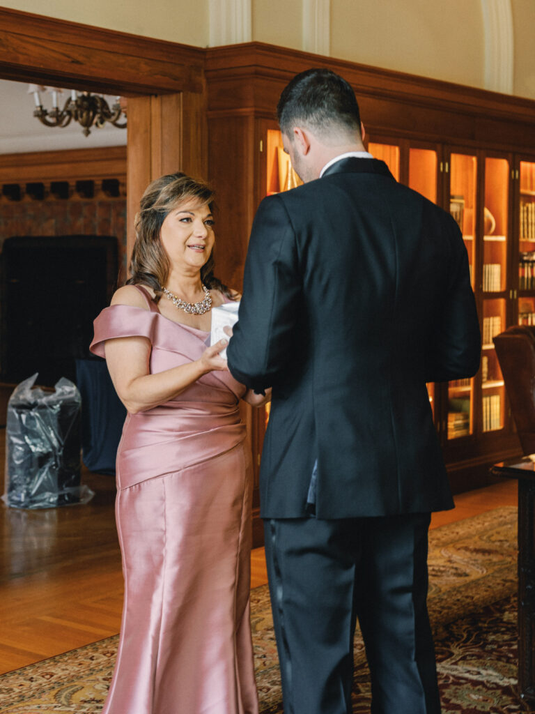 Emotional wedding day moment with the groom and his mother exchanging gifts.
