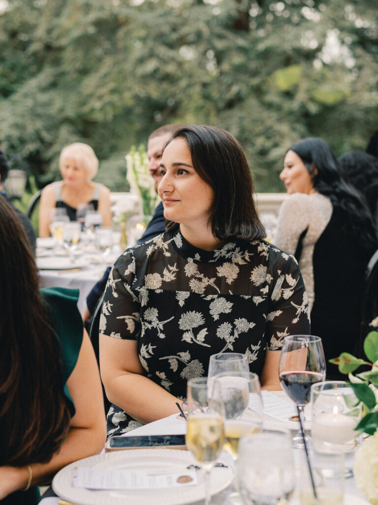 A close up wedding portrait of a female guest in an elegant dress during an outdoor ceremony at a luxury destination wedding venue