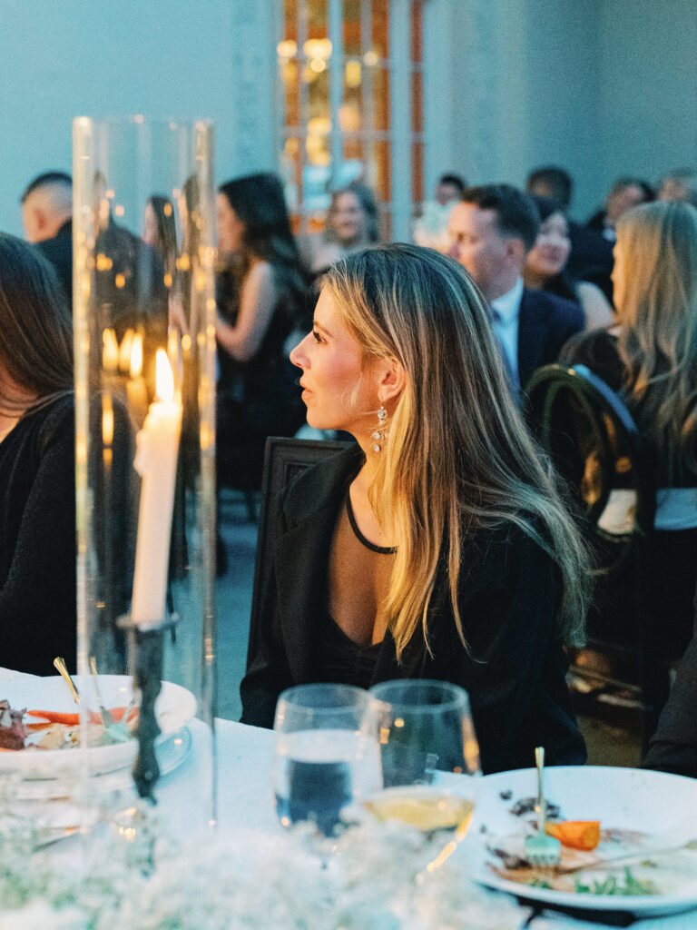Profile portrait of a wedding guest during a nighttime reception, capturing a candid moment under soft candlelight framing