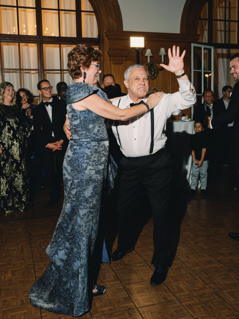 Lively wedding reception photoshoot featuring parents of the couple dancing and celebrating on the dance floor.