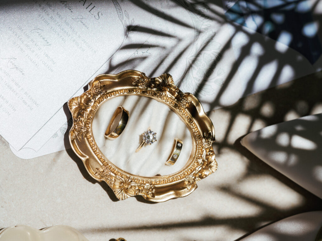 Luxury diamond engagement ring and gold wedding bands on a vintage tray with bespoke stationery