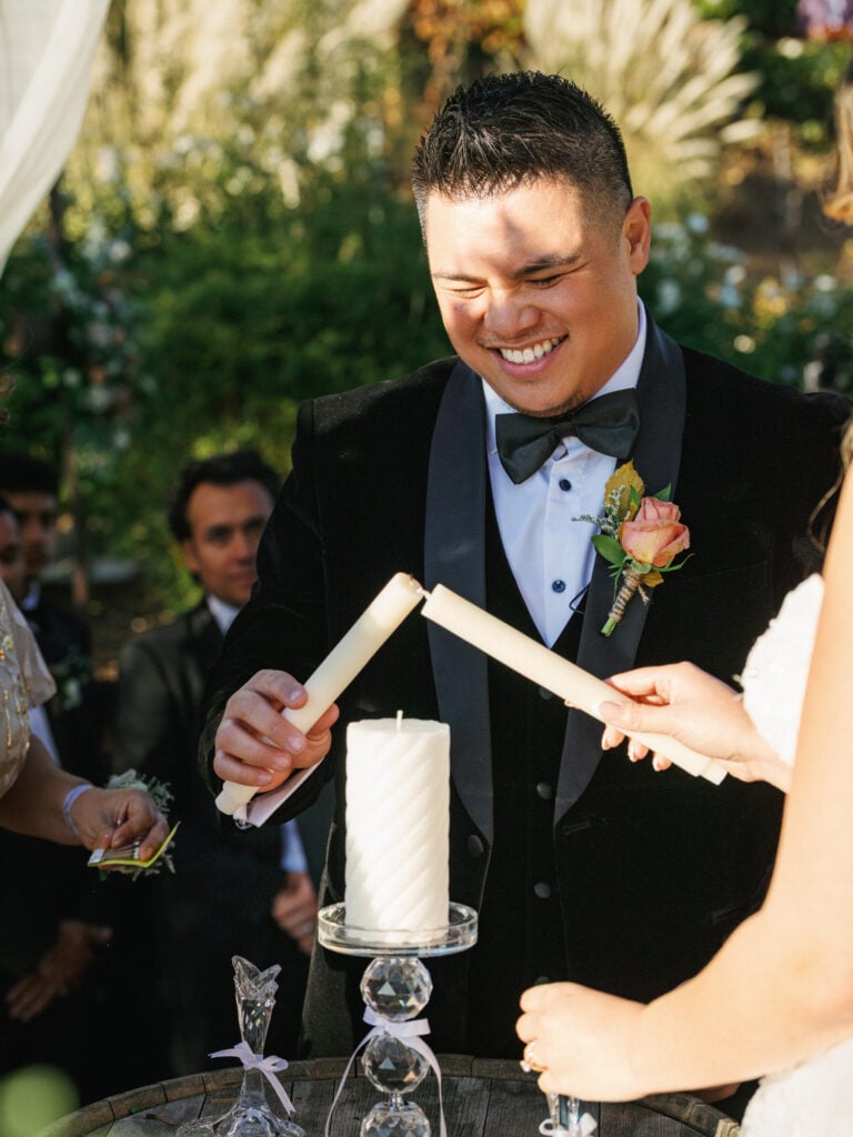 Bride and groom performing the unity candle ceremony during an elegant outdoor wedding