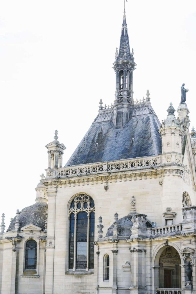 Historic French chateau wedding venue architecture with classic stone facades and slate roofs under soft daylight.