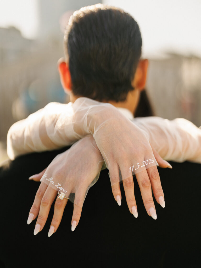 Creative wedding couple photoshoot focusing on the bride's hands in custom embroidered sheer gloves hugging the groom.