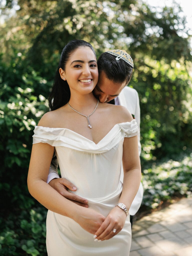 Candid wedding photography of a groom kissing the bride on the neck during their portrait session