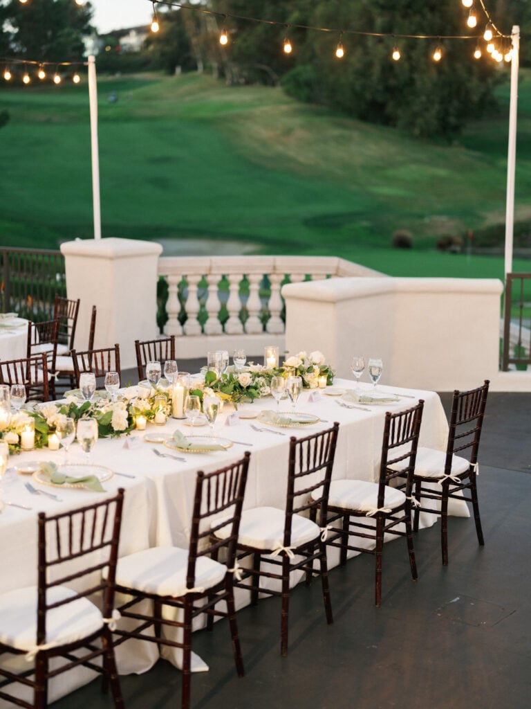 Elegant outdoor wedding reception tablescape with floral runners and candlelit decor