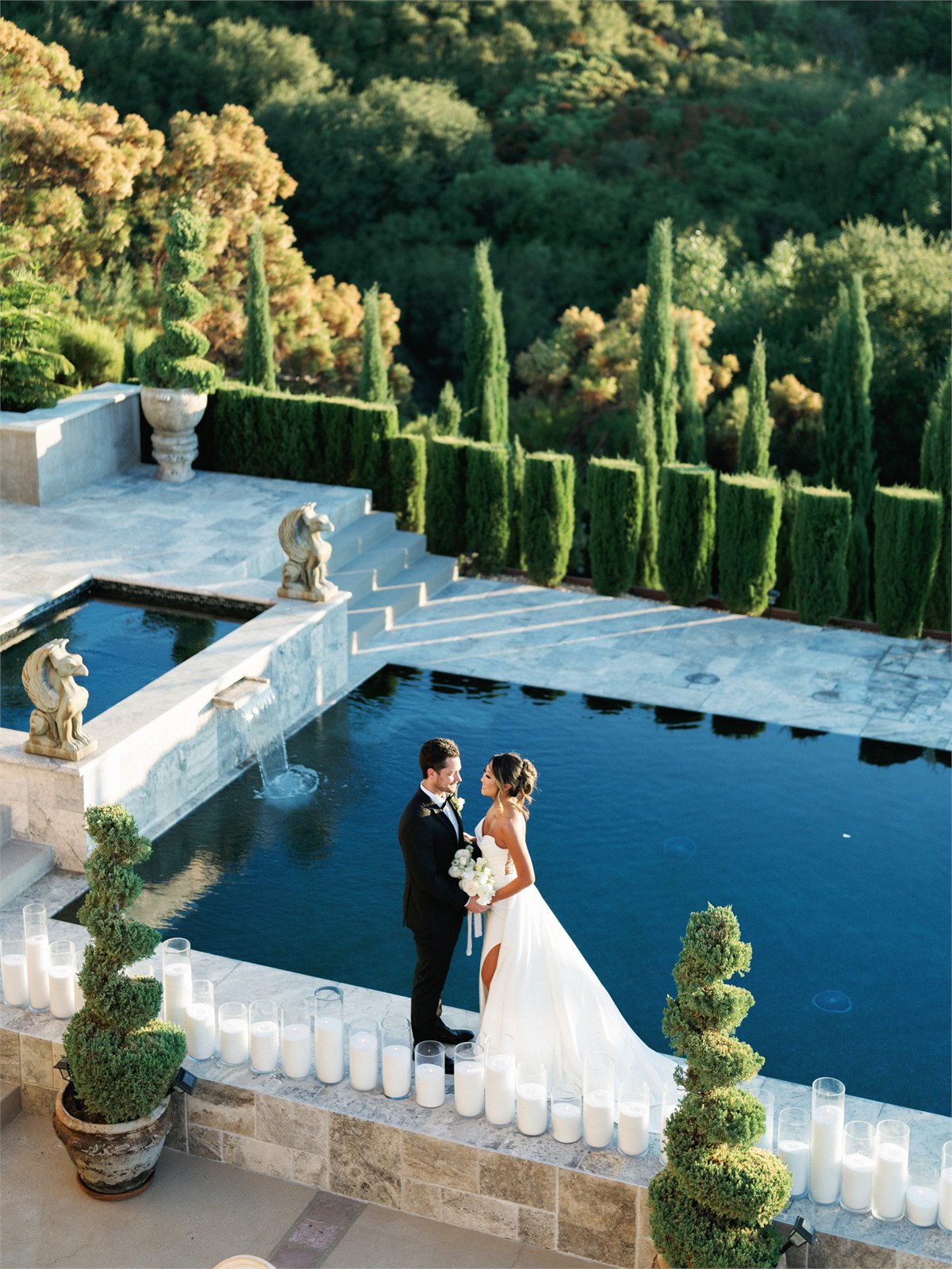 Wedding couple standing beside water and stone architecture