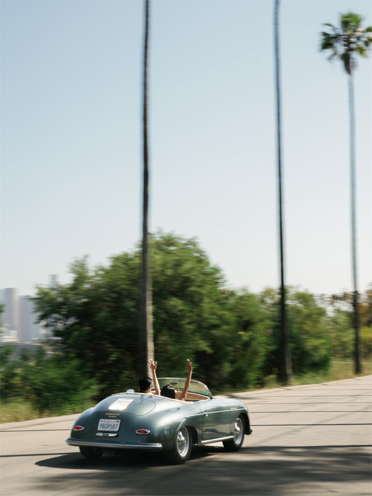 Vintage convertible driving along a palm-lined road