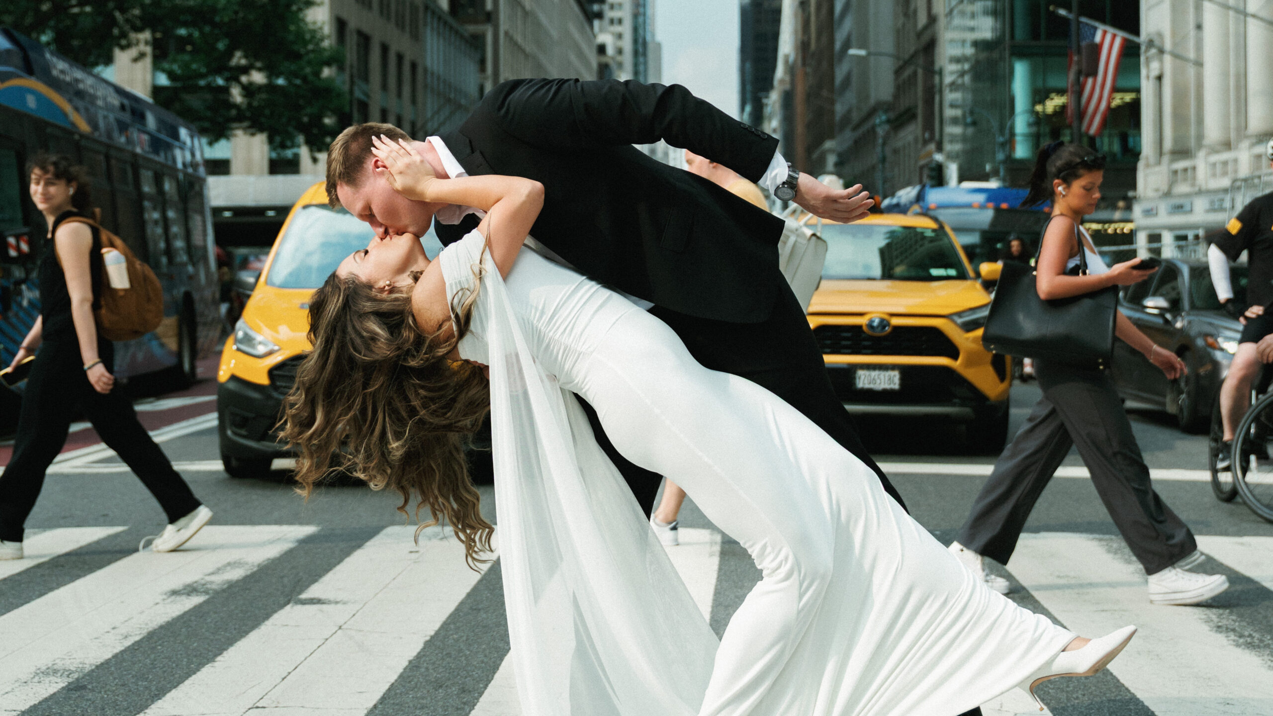 Cinematic New York City wedding photography of a newlywed couple kissing in the middle of a busy street in downtown NYC.