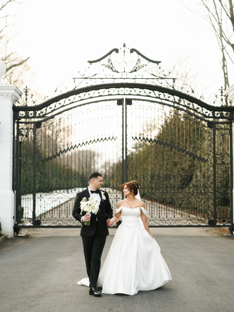 An elegant newlywed couple shares a romantic look outside the grand entrance of a historic Southern California private villa.