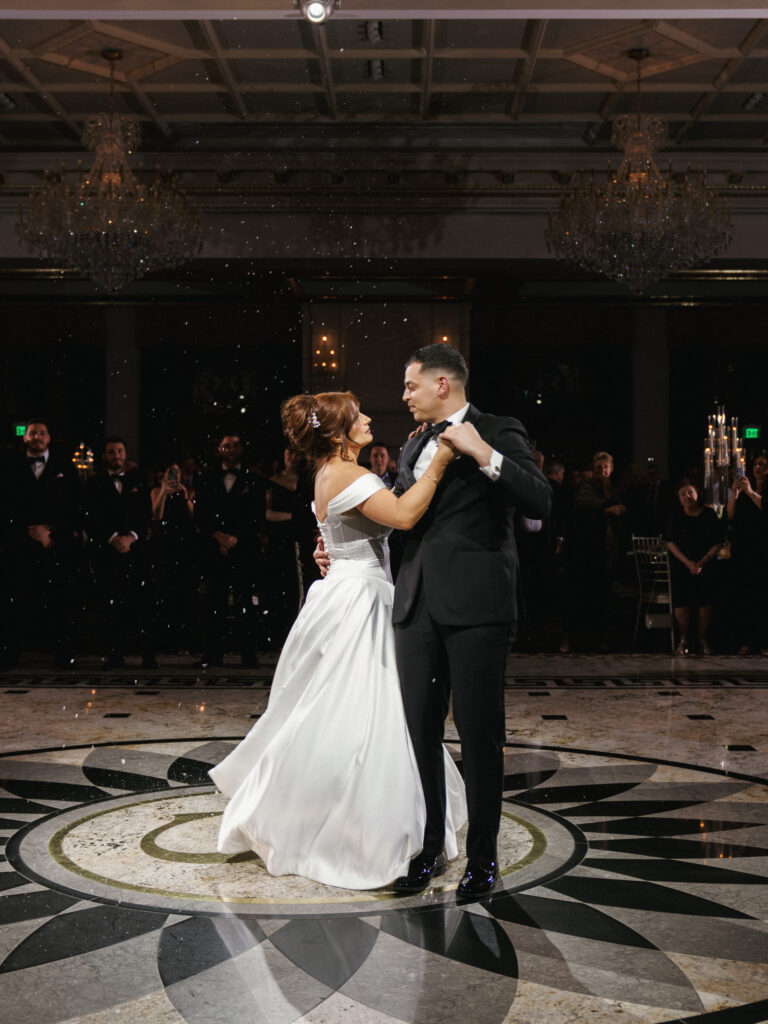 Luxury Manhattan wedding photography of a newlywed couple dancing under sparkling indoor confetti at a black-tie reception.