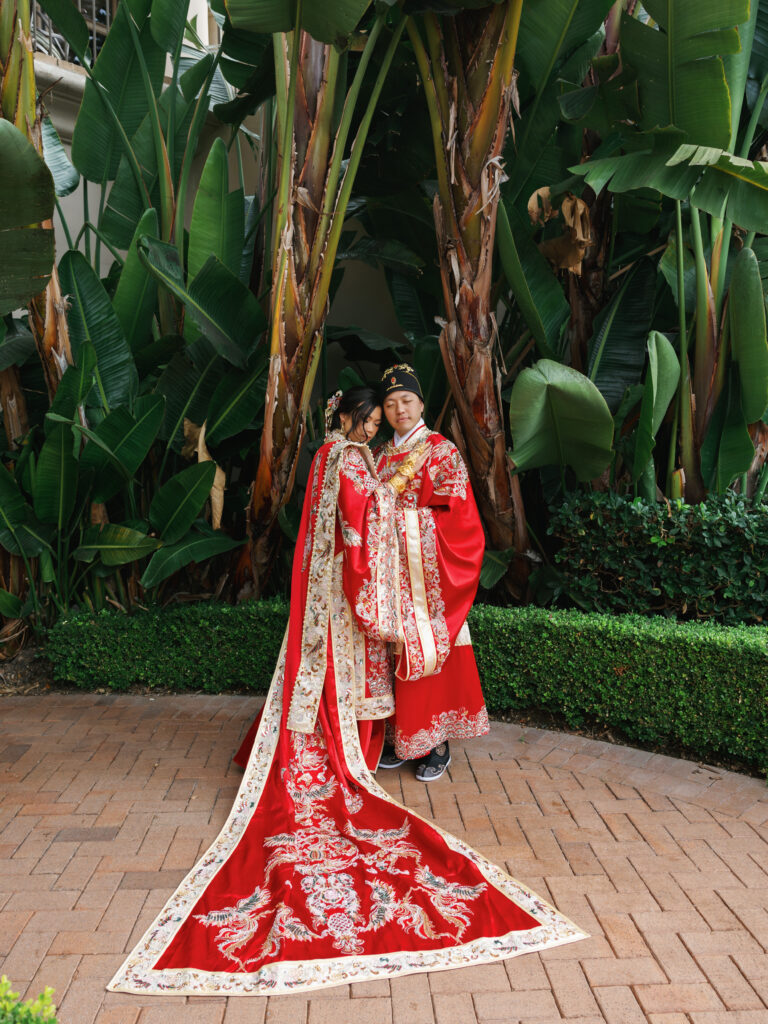 Editorial wedding portrait of a bride and groom wearing traditional Chinese Xiuhefu garments at a multicultural wedding.