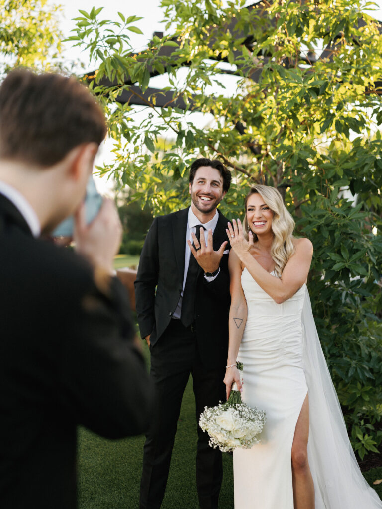 Behind-the-scenes wedding photography moment showing a professional photographer capturing a joyful bride and groom.