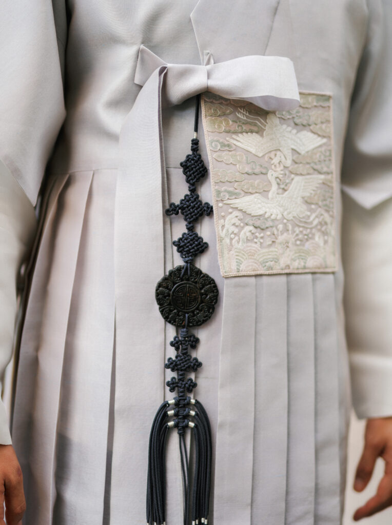 Close-up of a traditional Korean Hanbok with a dark Norigae tassel and elegant crane embroidery details.