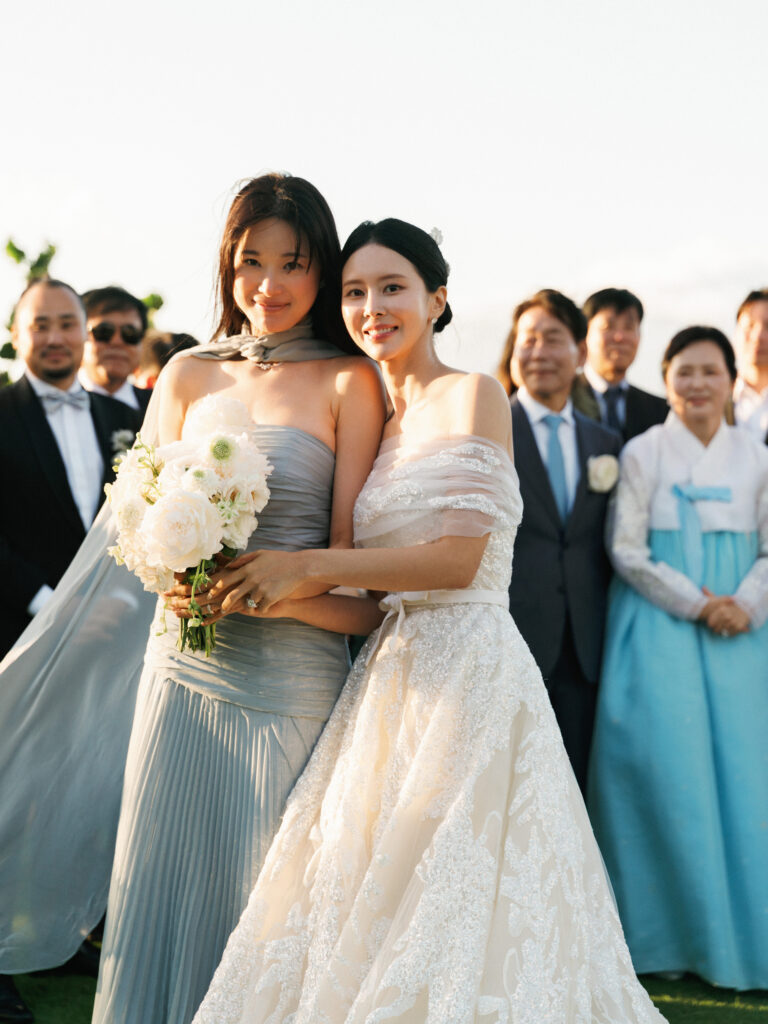 Elegant bridesmaids traditions inspiration featuring a luxury bride and her maid of honor posing with a white flower bouquet.