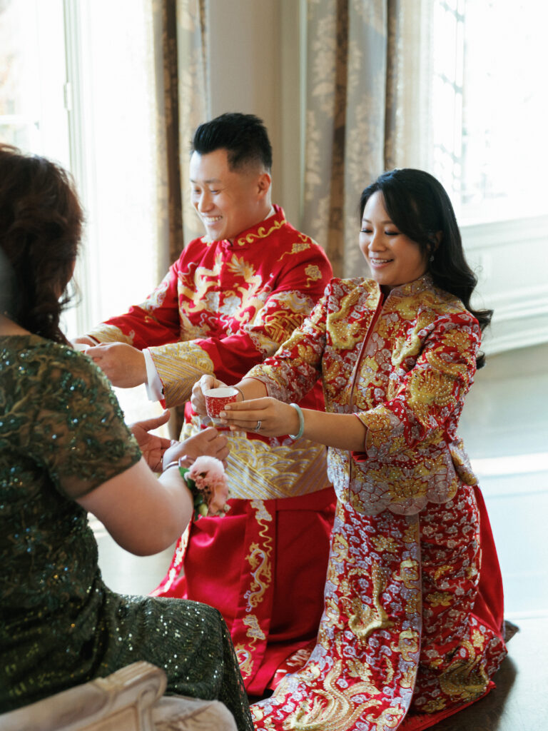 Bride and groom serving tea during a traditional Chinese tea ceremony at a multicultural wedding.