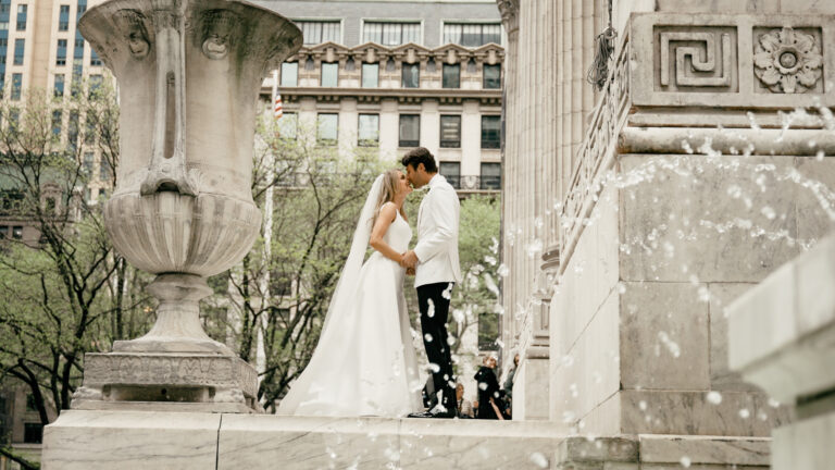 A bride and groom kiss outside the historic New York Public Library wedding venue on Fifth Avenue in Manhattan.