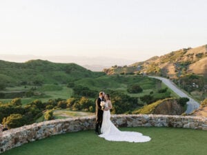 A bride and groom kissing on the scenic overlook at Cielo Farms wedding venue in Malibu, surrounded by rolling green hills.