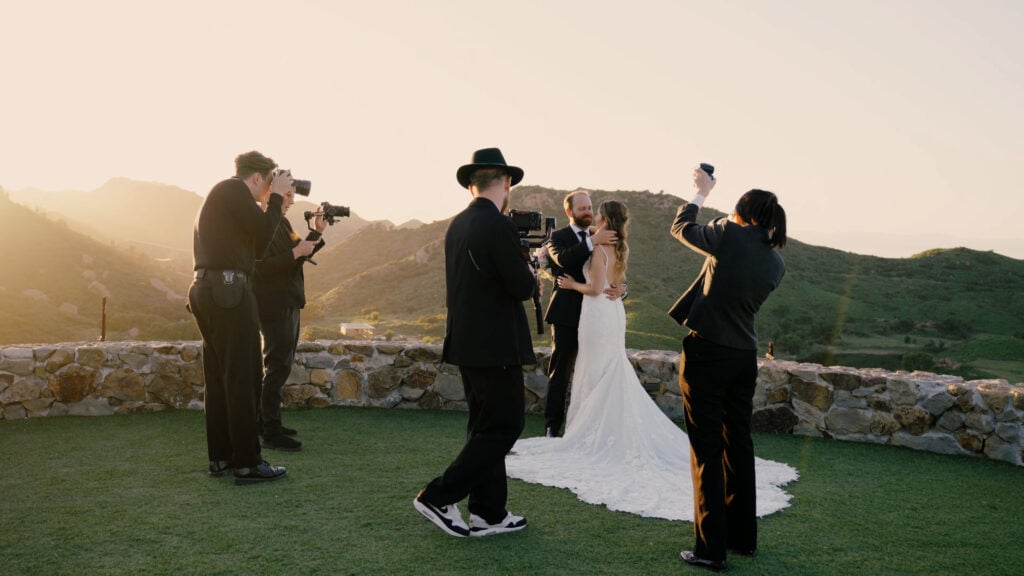 Behind-the-scenes of a luxury media production team filming a bride and groom on the panoramic stone terrace at Cielo Farms in Malibu.