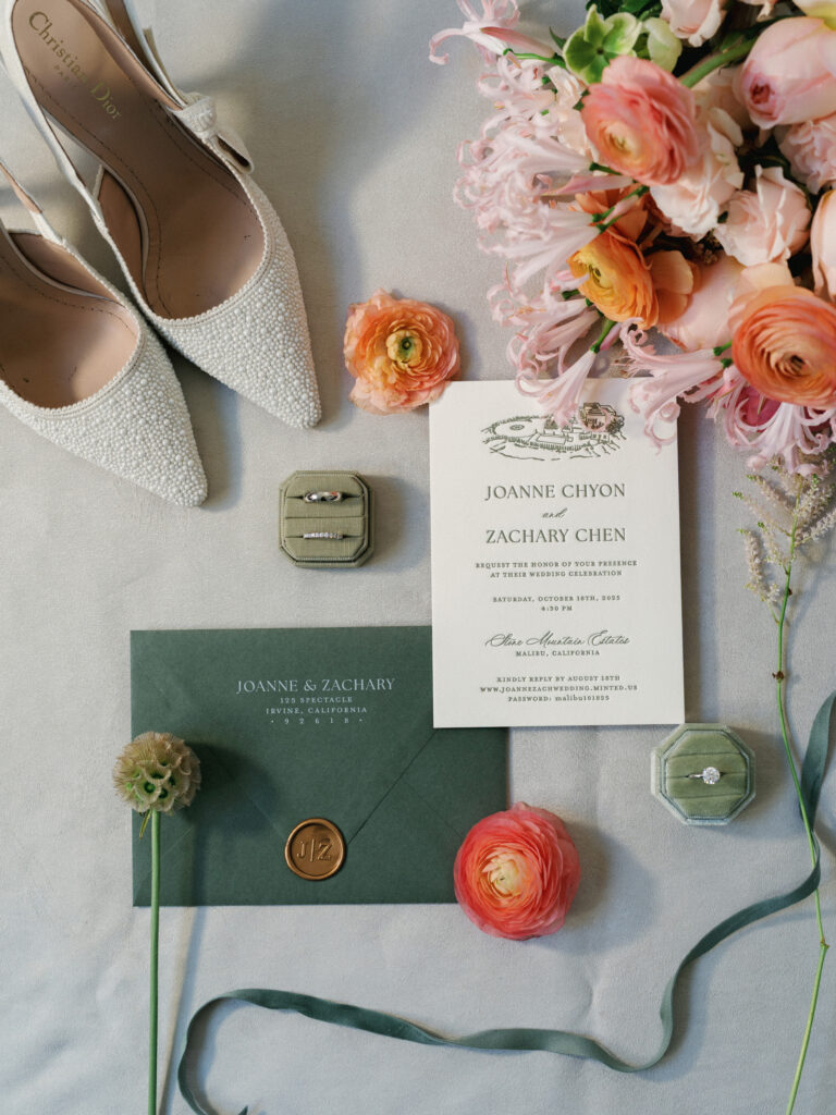 Elegant wedding invitation flat lay for Joanne and Zachary's wedding at The Mountain Mermaid in Topanga California, featuring white Christian Dior heels and green velvet ring boxes.