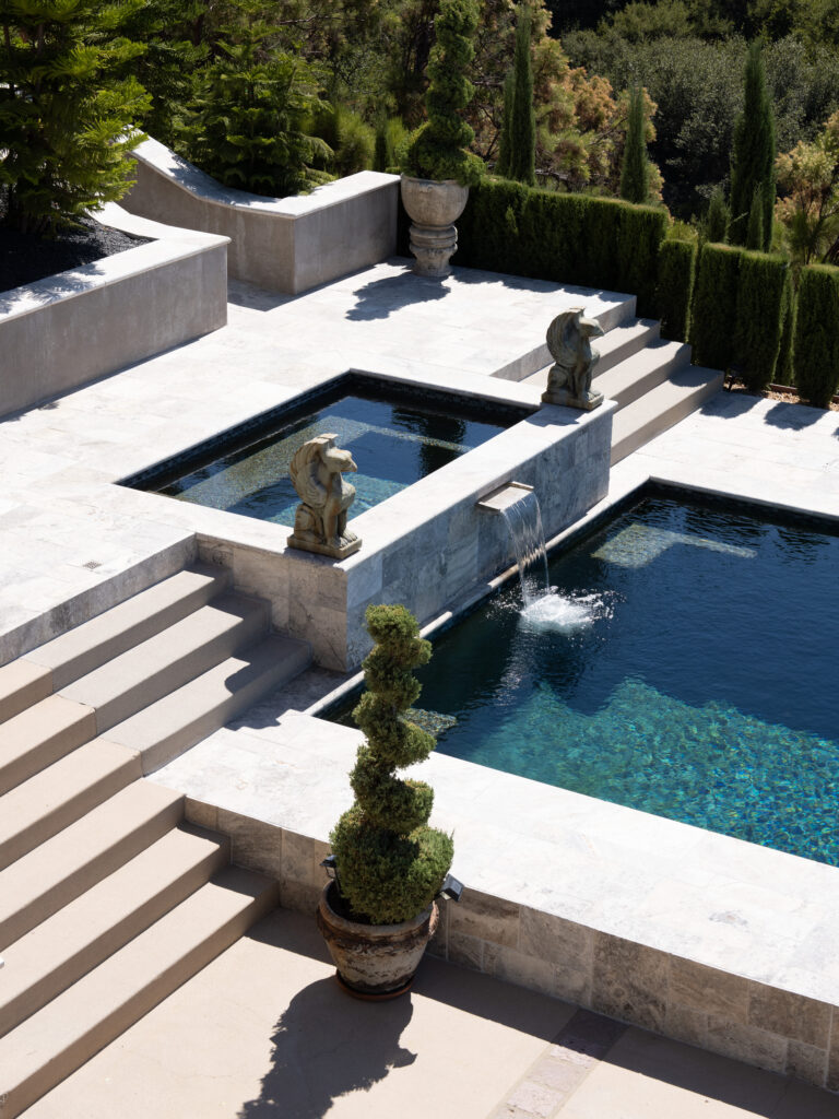 Vertical landscape photography at Greystone Mansion, highlighting the clean stone architecture of a reflection pool, sharp shadows on stairs, and a lush forest backdrop.