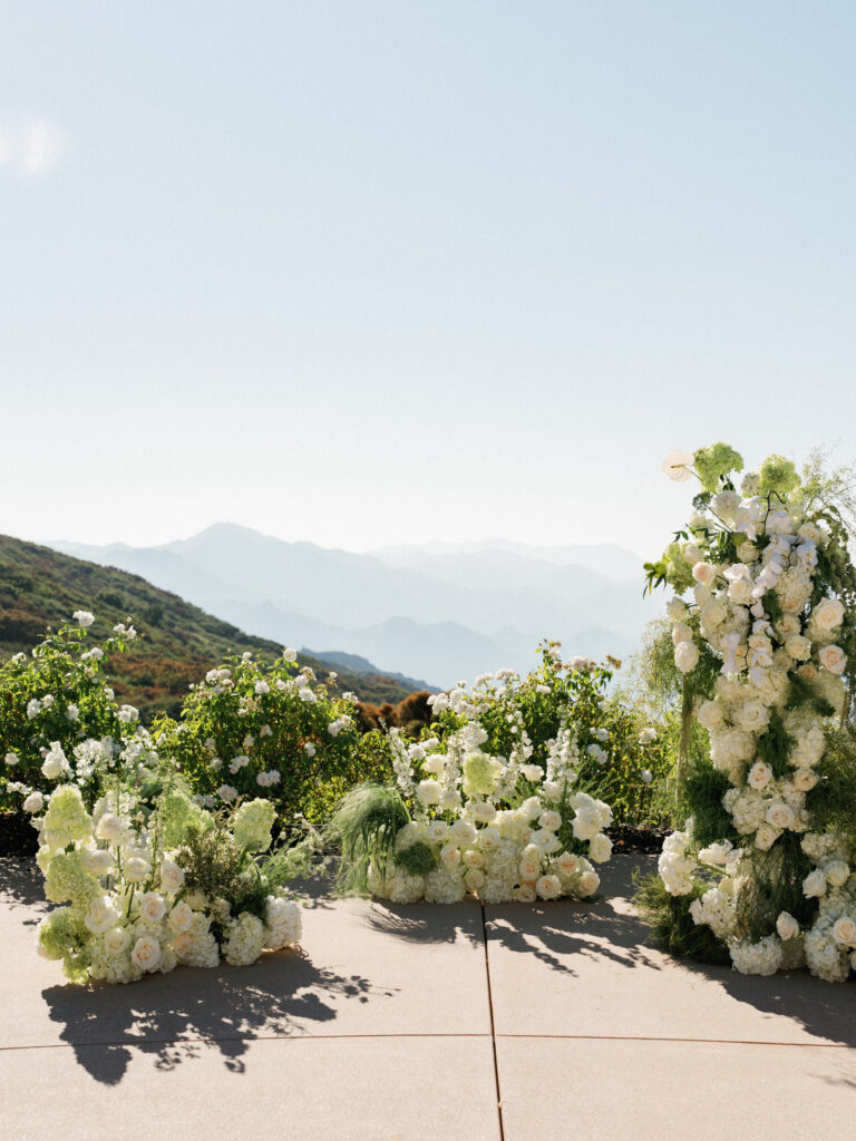 Outdoor wedding ceremony altar setup at the Formal Gardens of Greystone Mansion, featuring white delphinium and hydrangea floral installations with a panoramic view of rolling hills.