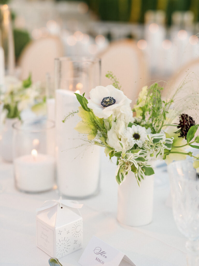 Elegant California wedding reception decor with modern white flower arrangements, personalized favor boxes, and romantic candle lighting.