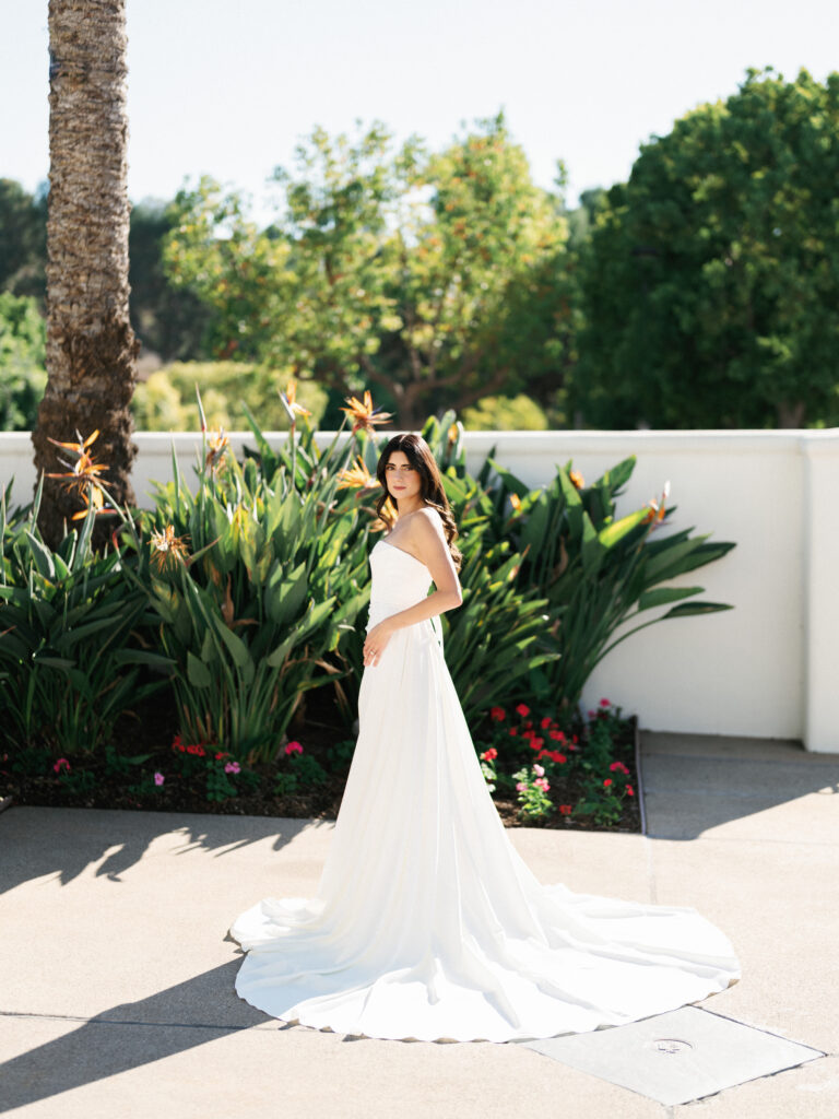 A bridal portrait at a luxury Beverly Hills estate wedding, featuring a bride in a strapless gown against tropical bird of paradise plants.
