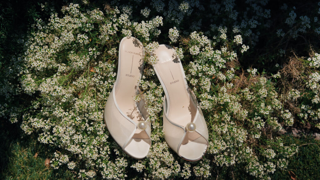 Black Suede Studio wedding mules with pearl detail, chic luxury bridal shoes display inspiration for a garden estate wedding.