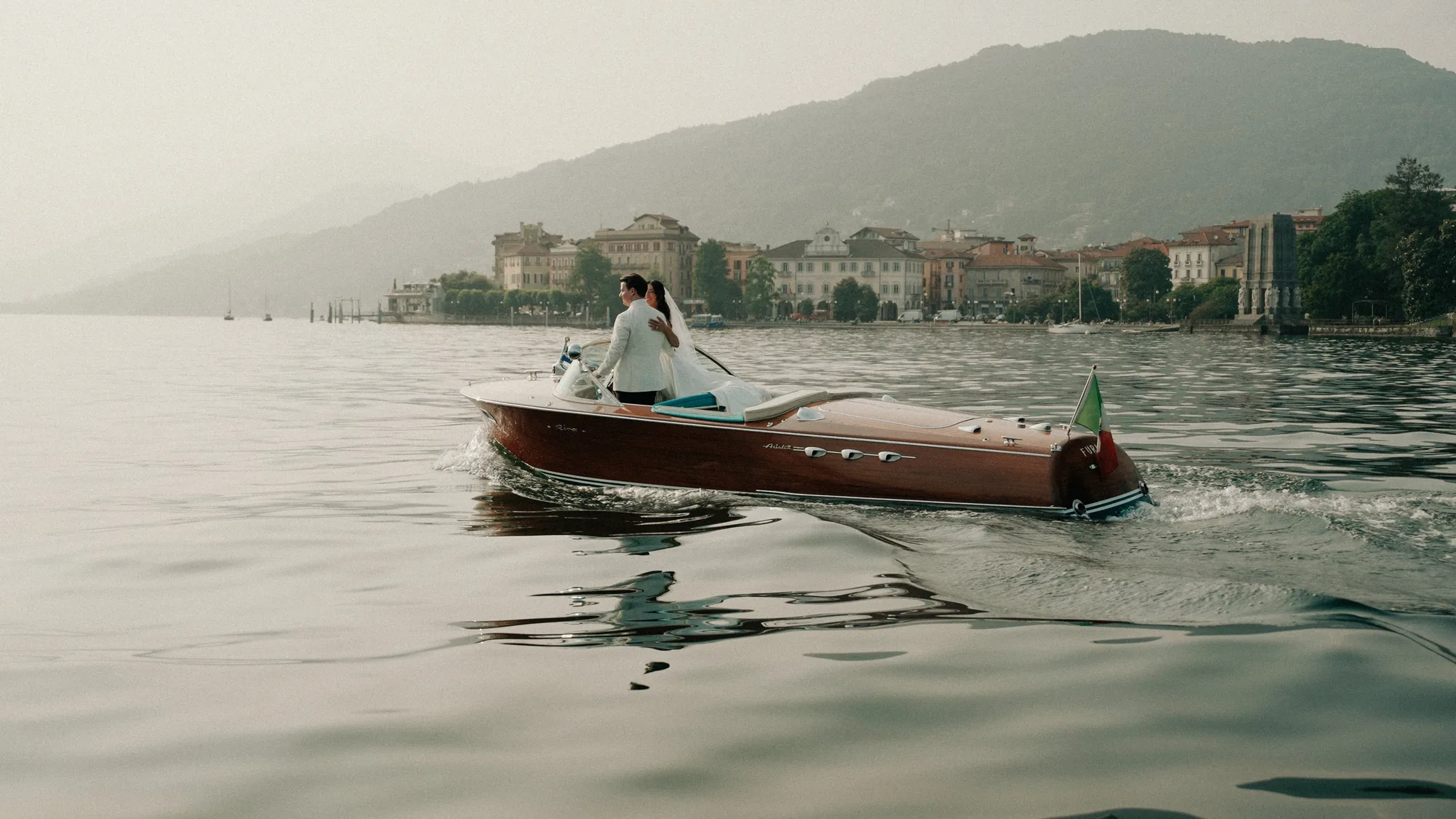 Wedding couple riding in a classic boat on a mountain lake
