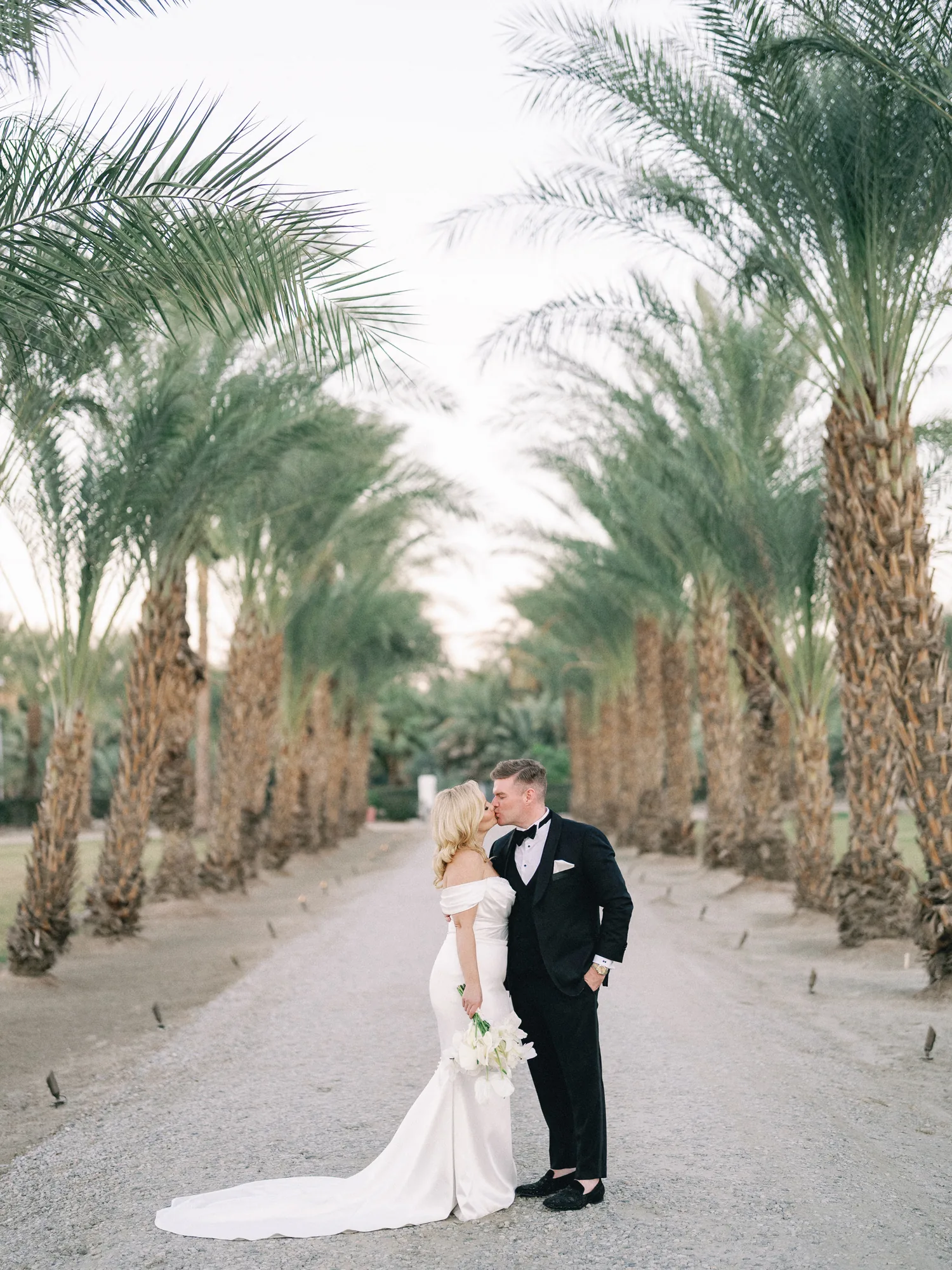 Wedding couple standing beneath tall palm trees