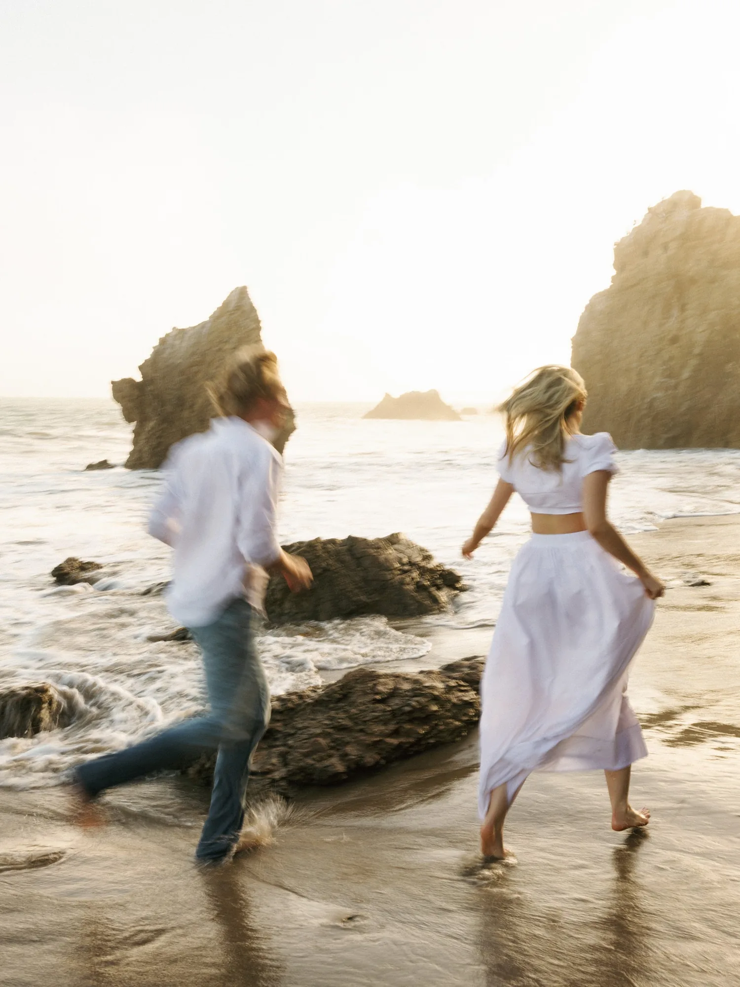 Wedding couple running together along a rocky coast