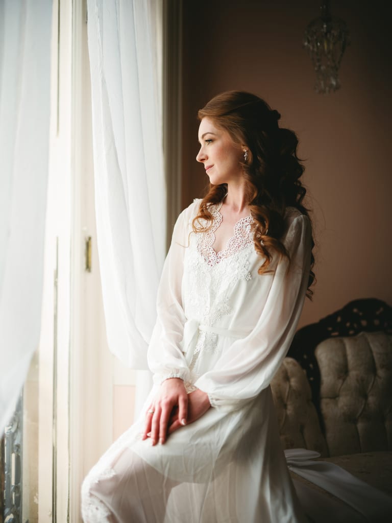 Bride standing beside a window before the ceremony