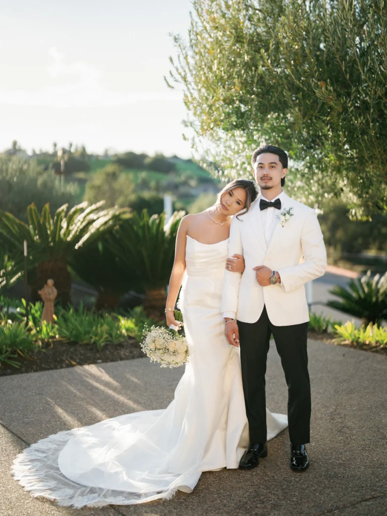 Golden hour wedding photography of a couple posing under an olive tree with soft sunlight illuminating the bride’s veil.