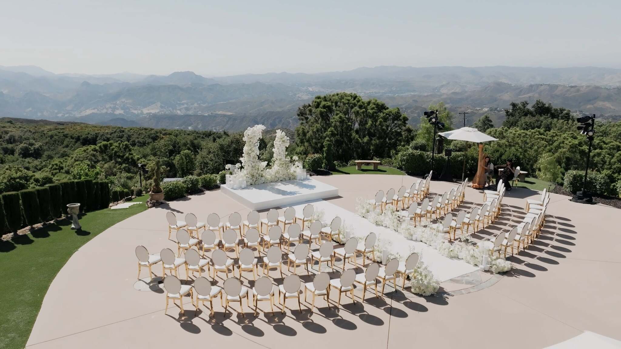 Outdoor ceremony setup with rows of chairs and a central aisle overlooking green hills.