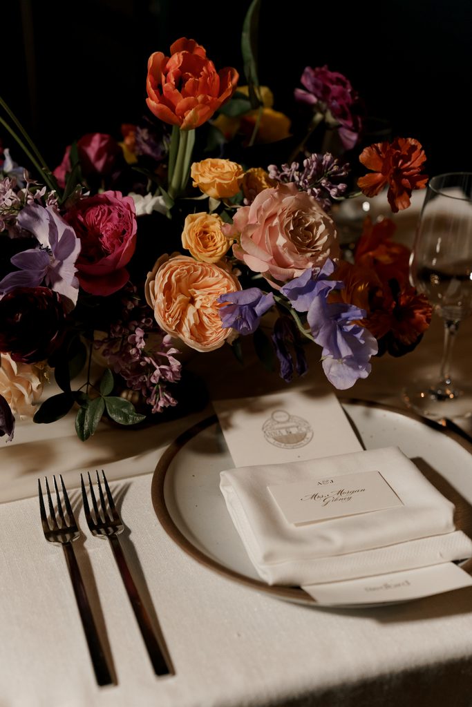 Vibrant floral centerpiece with colorful roses and tulips adds a romantic touch to this elegant wedding table setting.