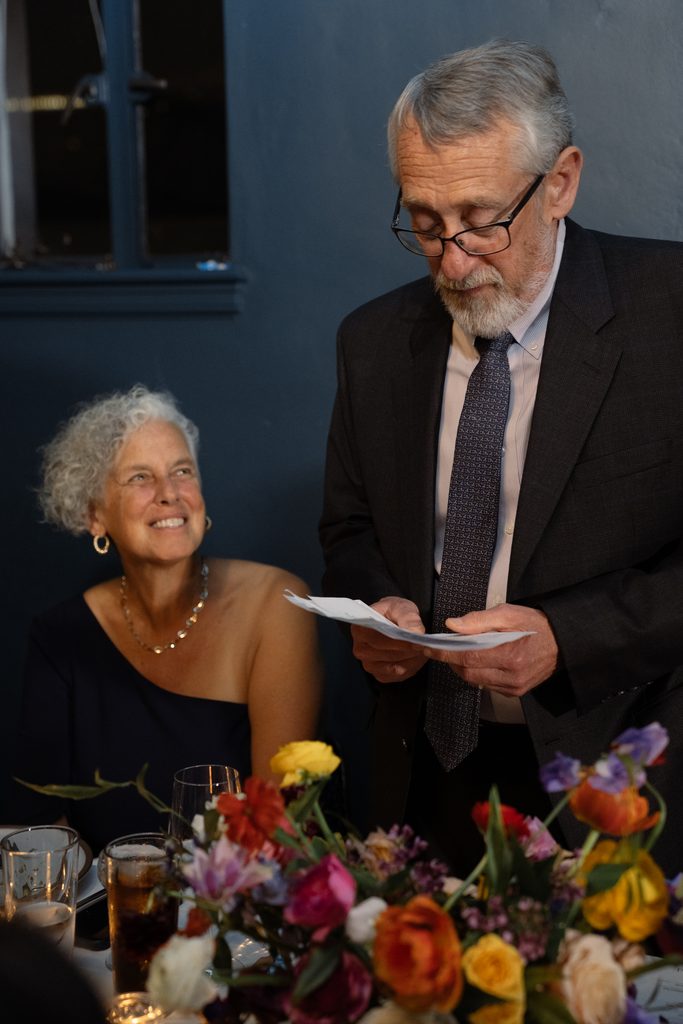 Proud parents share a meaningful toast during an intimate dinner, captured in timeless wedding reception photos.