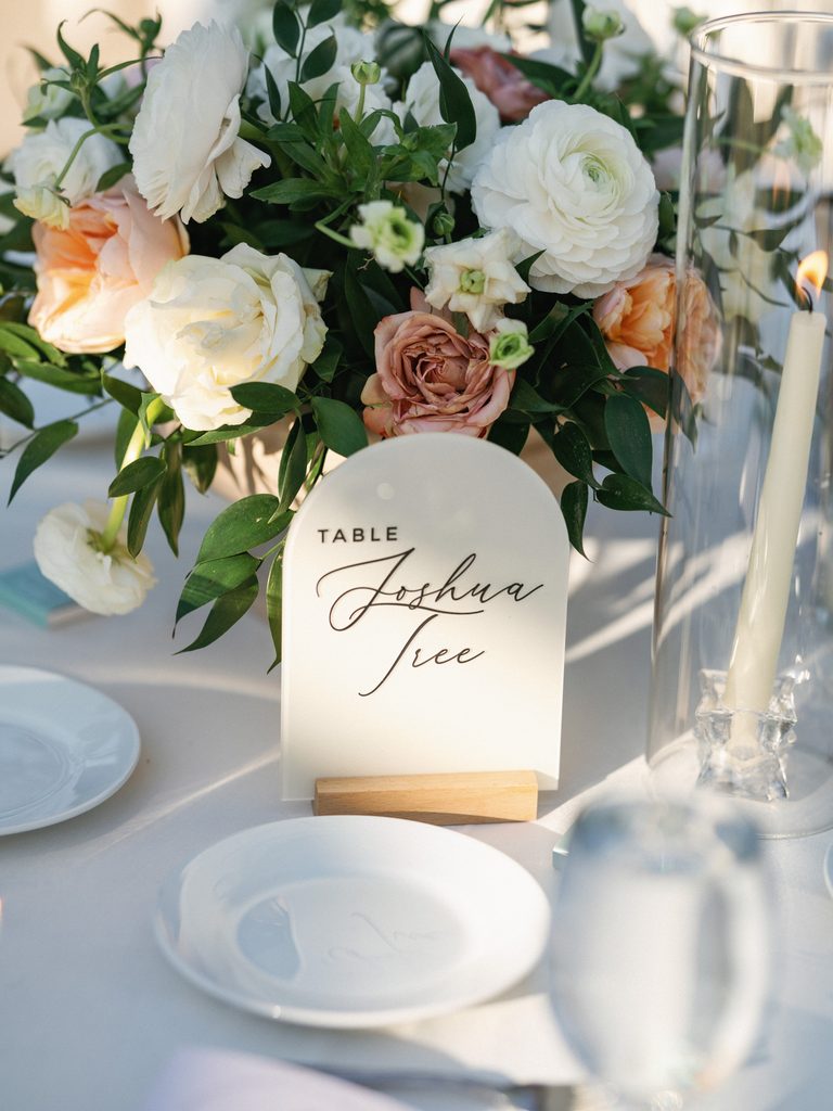 Elegant wedding reception photos showing a custom acrylic table name sign next to a floral centerpiece.