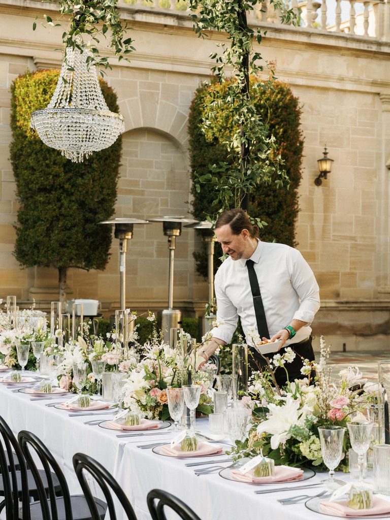 Professional venue staff sets up a luxury outdoor dinner table in these behind the scenes wedding reception photos