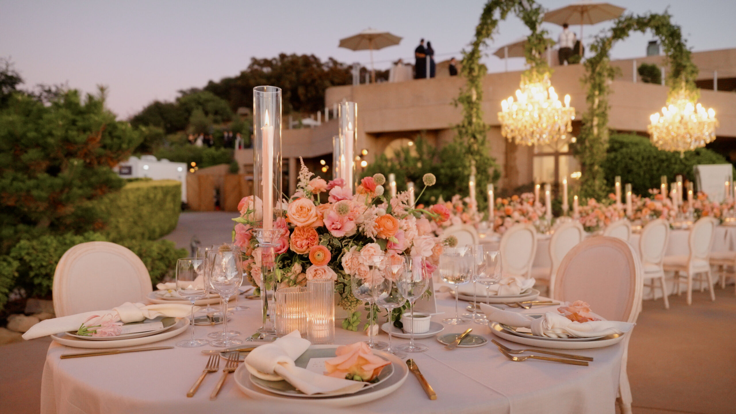 Outdoor wedding reception tables with flowers and chandeliers