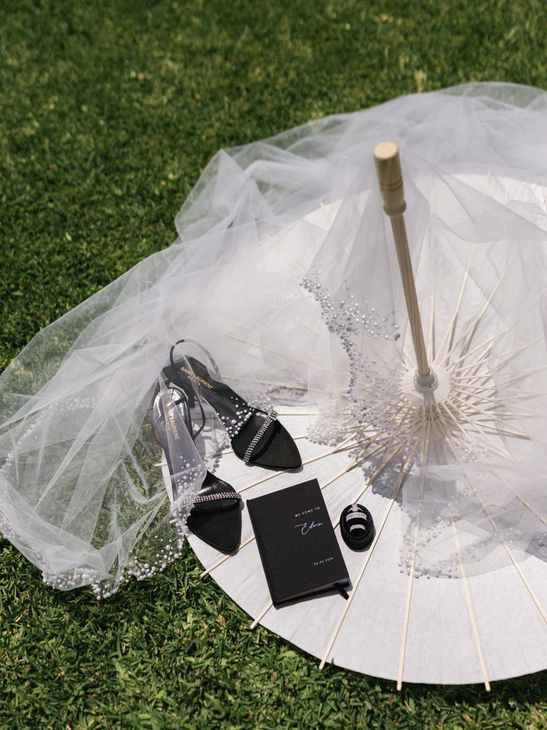 Luxury bridal flat lay with a sheer veil and white paper parasol on grass