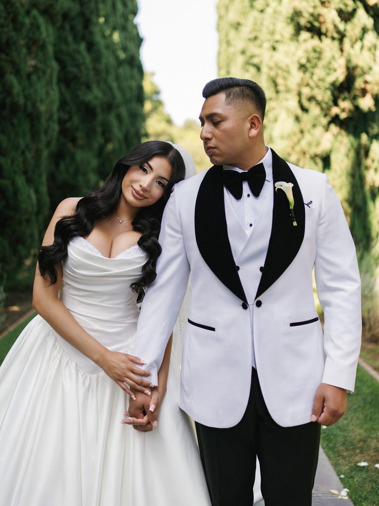 Beautiful bride leaning her head on grooms shoulder while holding hands outdoors