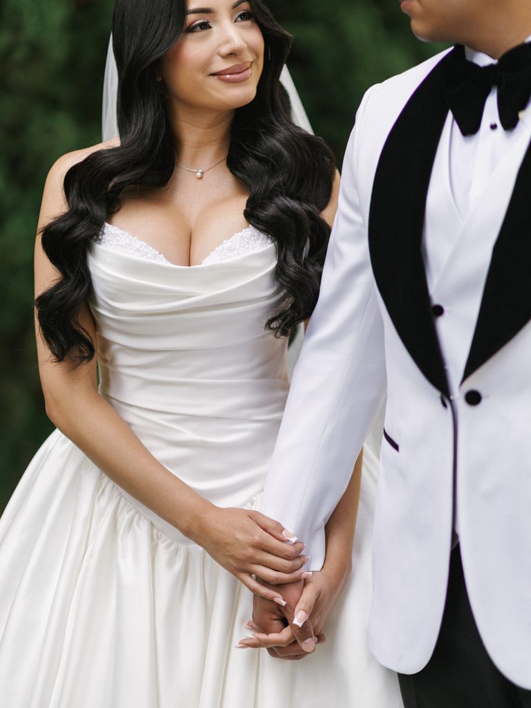 Stunning bridal look featuring long dark waves and a draped white satin ballgown