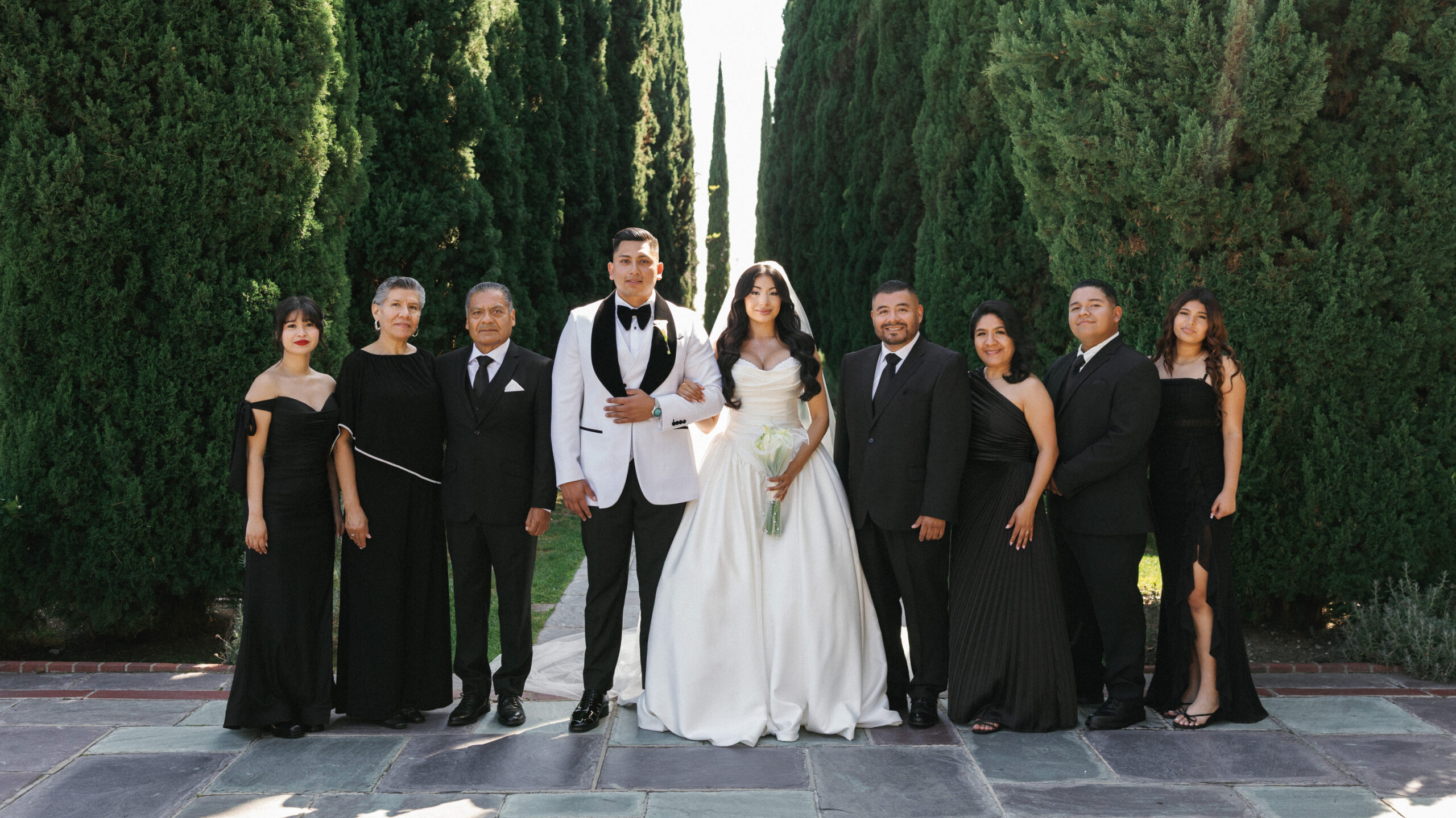 Elegant group wedding portrait featuring newlyweds with their family members in formal black attire