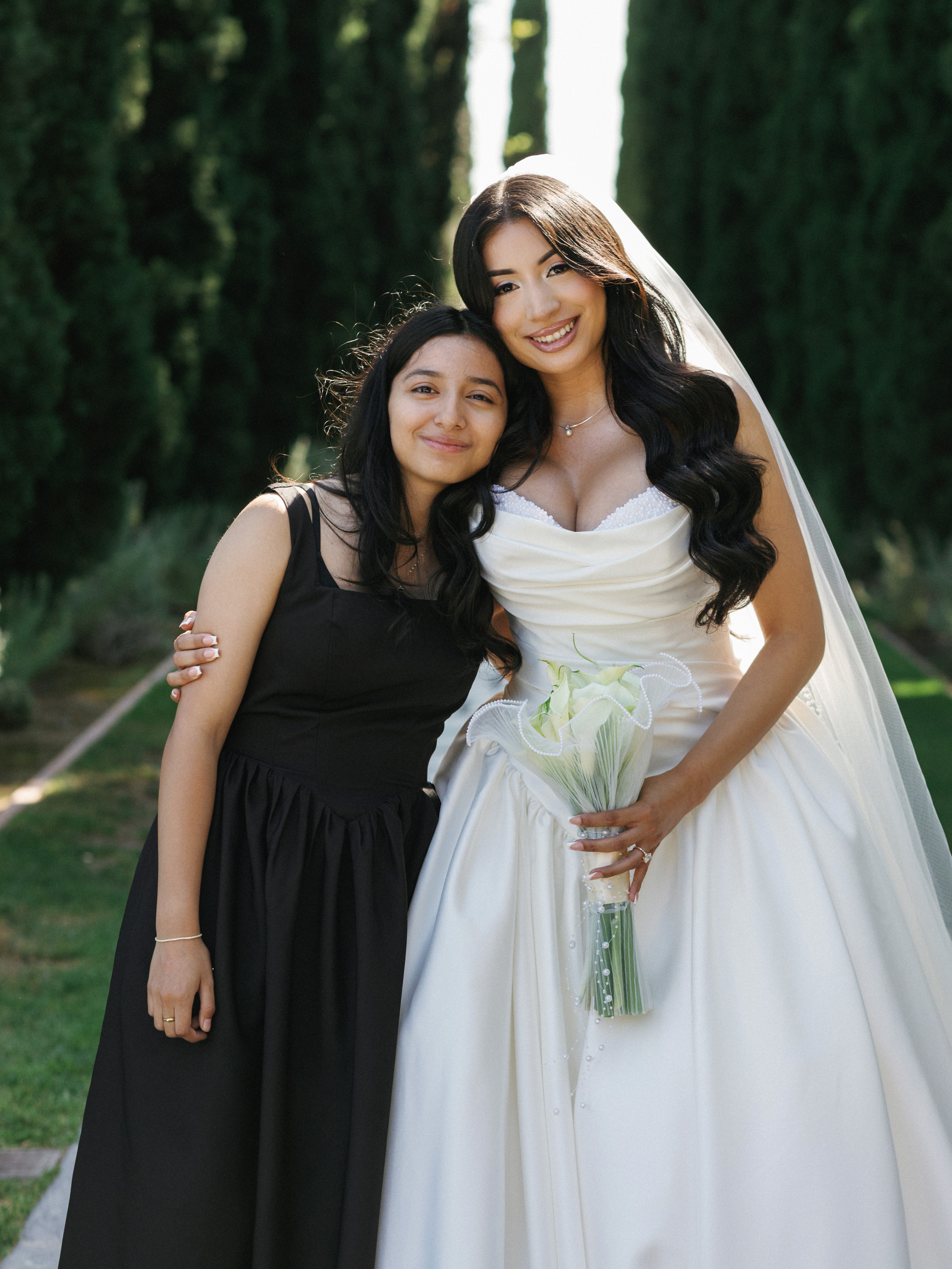 Stunning bride posing with her sister in a sleek black dress outdoors