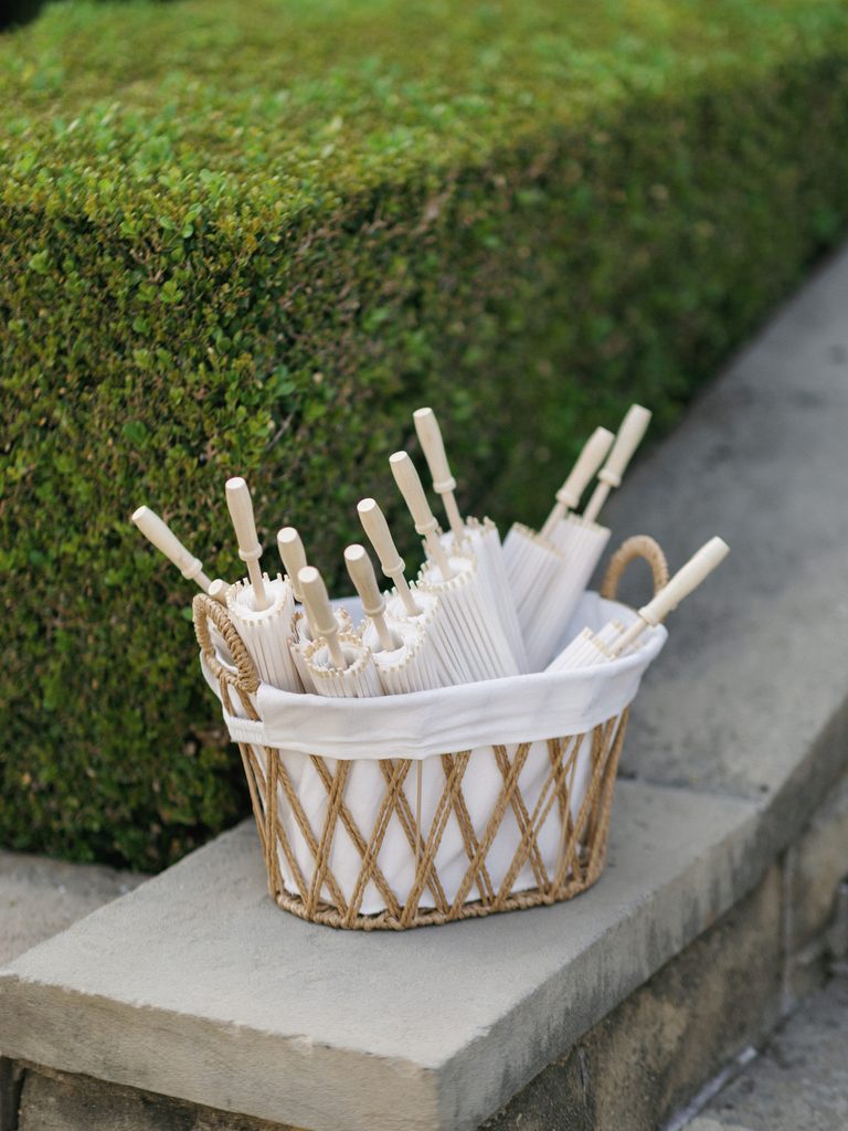 Luxury wedding guest favor ideas with classic wooden umbrellas next to green hedges