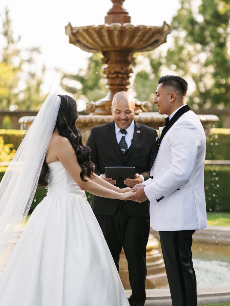 Elegant garden ceremony setup with a historic stone water fountain backdrop